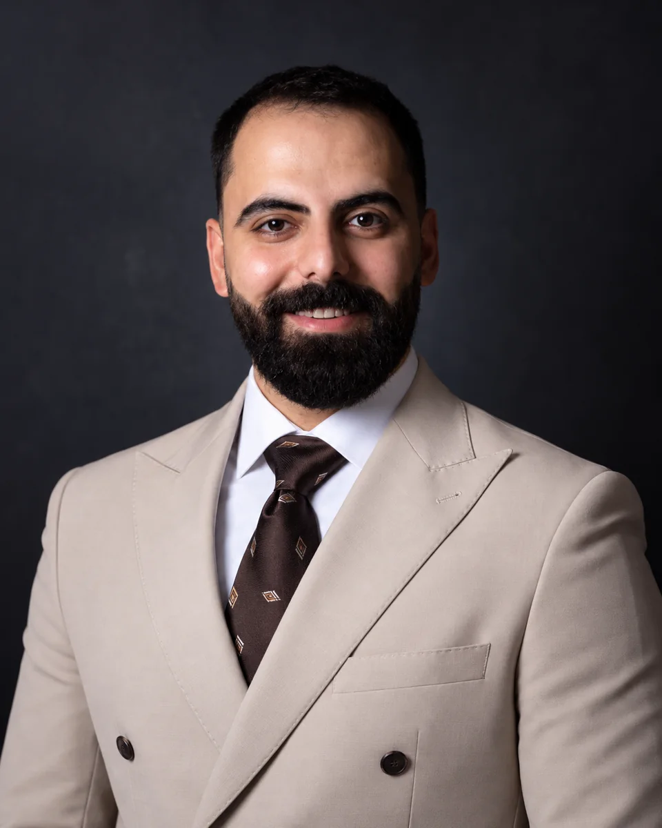 Portrait of Wesam Kahwaji in a light double-breasted suit against a dark backdrop